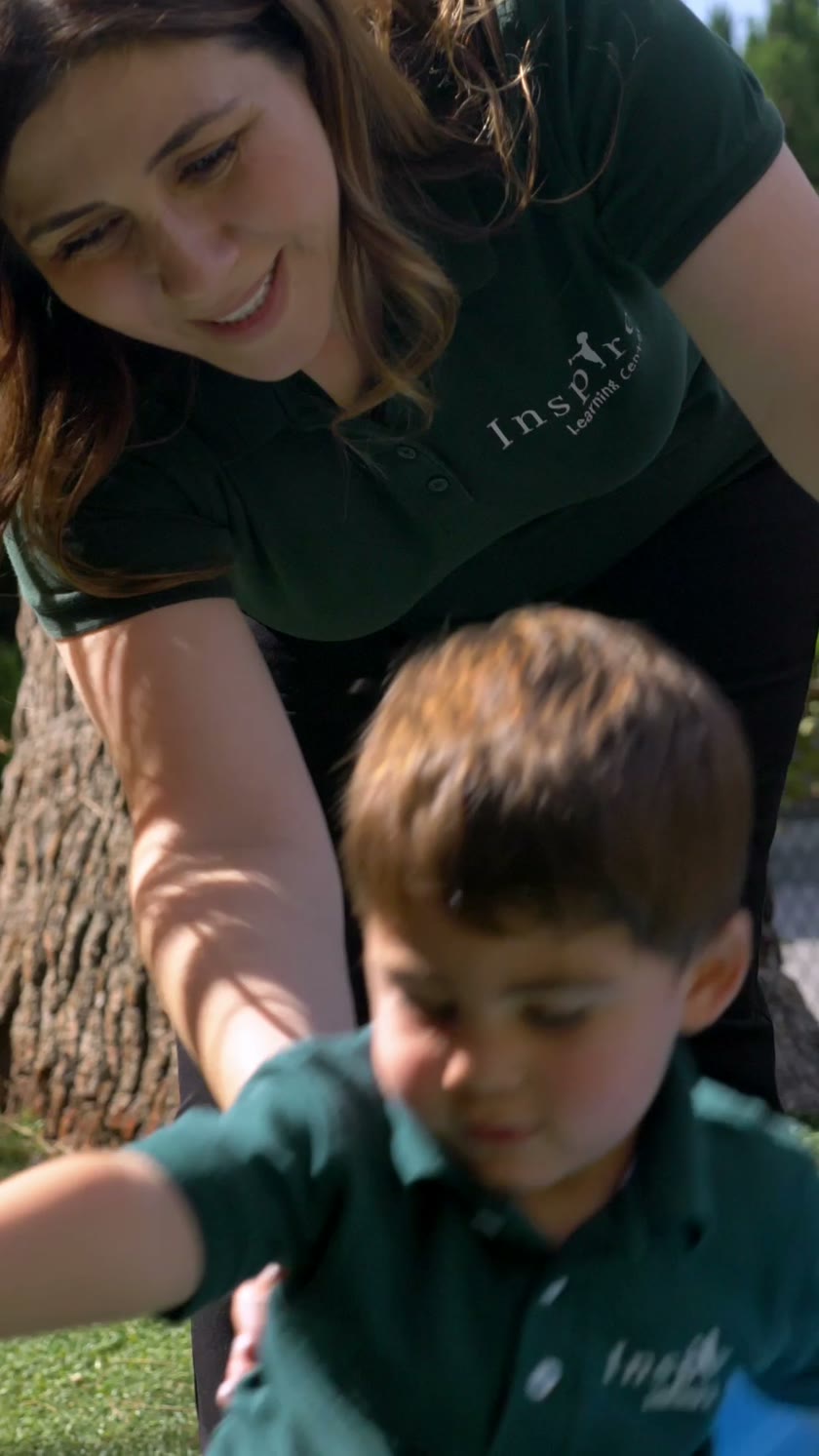An Inspire teacher supporting a child during outdoor play